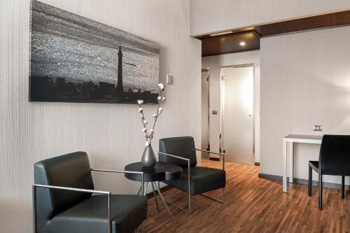 a living room with a table and chairs and a desk at AC Hotel Palacio Universal by Marriott in Vigo