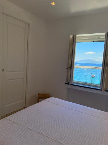 una camera da letto con finestra affacciata sull'oceano di La Baia di Napoli a Capri