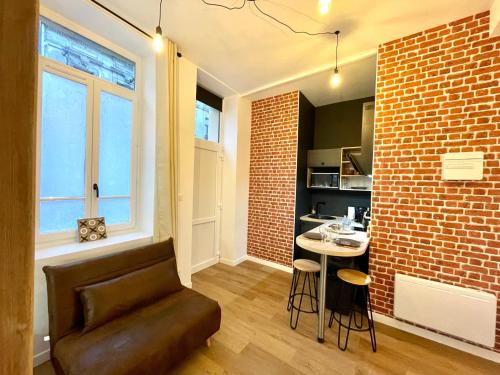 - un salon avec une chaise et un mur en briques dans l'établissement LE VOLTA - Appartement - Centre ville Calais, à Calais