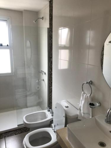 a white bathroom with a toilet and a sink at Depto en Tucumán in San Miguel de Tucumán