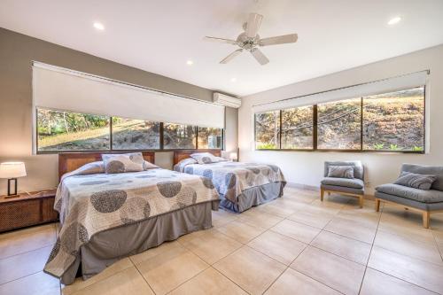 two beds in a room with large windows at Casa Carmen in Potrero