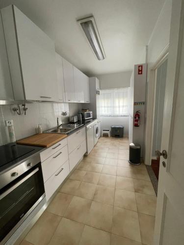 uma cozinha com armários brancos e piso em azulejo em Parque Verde 1 - AL em Torres Vedras