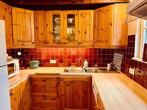 a kitchen with wooden cabinets and a sink at Den Haegepreeck in Horebeke