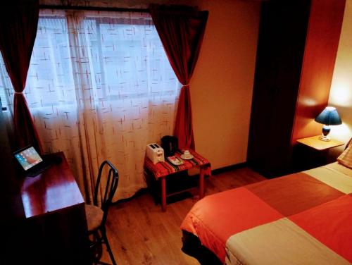 a hotel room with a bed and a table and a window at Casa de Huéspedes Tu Parada en Cuenca in Cuenca