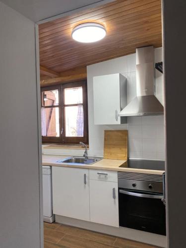 cocina con armarios blancos, fregadero y fogones en Casa Alba, en Taüll