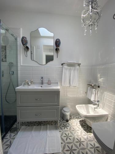 a white bathroom with a sink and a mirror at La Baia di Napoli in Capri