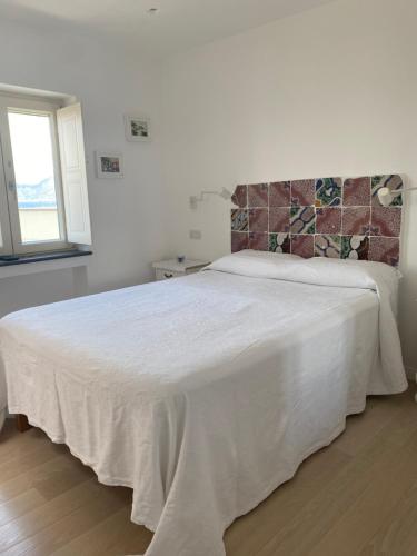 białe łóżko w białej sypialni z oknem w obiekcie La Baia di Napoli w mieście Capri