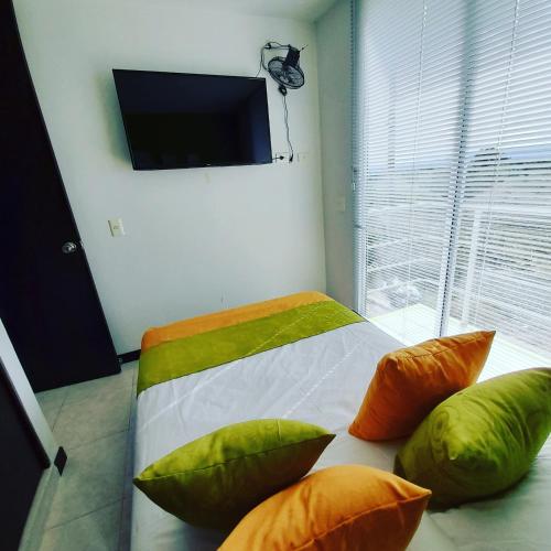 a bedroom with a bed with green and orange pillows at Aptos para tus vacaciones a 3 min del Parque del Cafe in Armenia