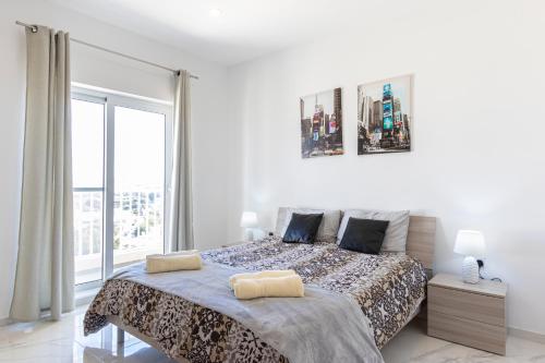 a white bedroom with a bed and a large window at H4- Modern Penthouse with Large Terrace and Views in San Ġwann