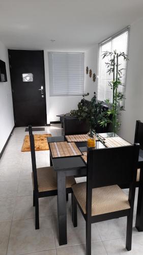 comedor con mesa negra y sillas en Apartamentos para tus vacaciones, en Armenia