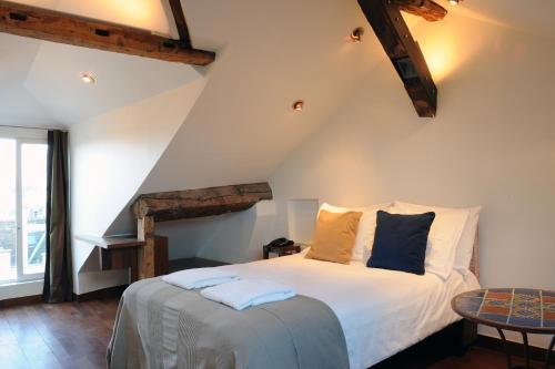 パリにあるブティック オテル デ ラ プラス デ ヴォージュのベッドルーム1室(白いシーツと青い枕のベッド1台付)