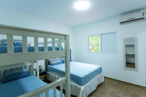 a bedroom with two bunk beds and a window at Paraíso Azul - Praia de Barequeçaba in Barequeçaba