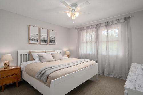 a white bedroom with a bed and a ceiling fan at Beach Twin B KDH123B in Kill Devil Hills