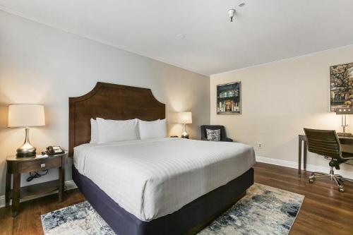 a bedroom with a bed and a desk and a chair at St Charles Inn, Superior Hotel in New Orleans