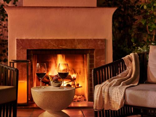 two glasses of wine on a table in front of a fireplace at Hotel Bel-Air - Dorchester Collection in Los Angeles