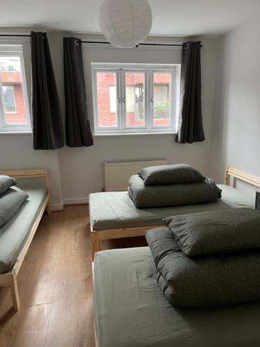 a room with two beds and two windows at Entire house with parking in Manchester