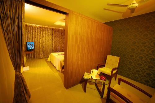 a room with a bed and a chair and a mirror at Hotel Chenduran Park in Dindigul