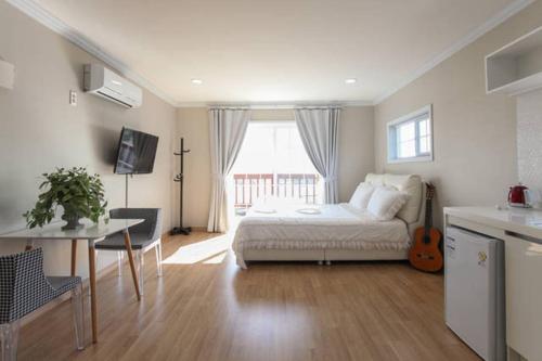 a bedroom with a bed and a table and a window at Jubilee Chalet in Seogwipo