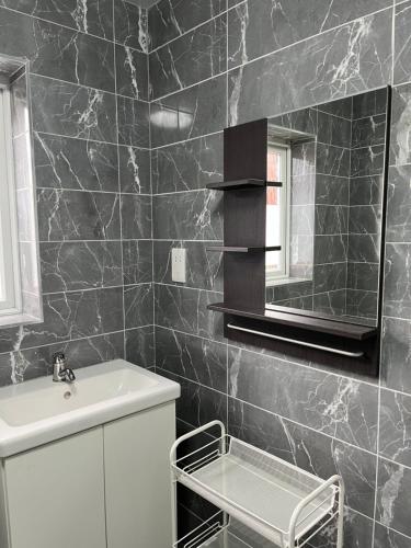 a black tiled bathroom with a sink and a mirror at Entire house with parking in Manchester