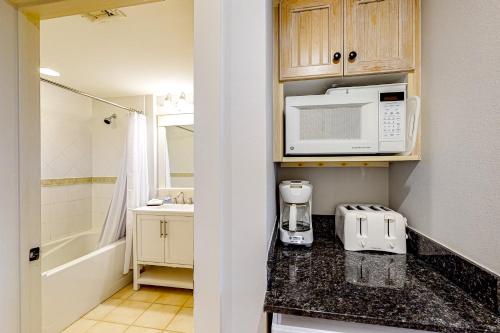 a kitchen with a counter with a microwave and a sink at Baytowne Wharf - Observation Point North #460 in Destin