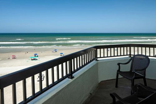 a chair sitting on a balcony looking at the beach at Best Western New Smyrna Beach Hotel & Suites in New Smyrna Beach