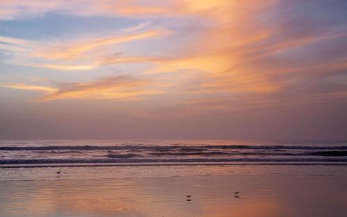 a sunset on a beach with waves in the ocean at Best Western New Smyrna Beach Hotel & Suites in New Smyrna Beach