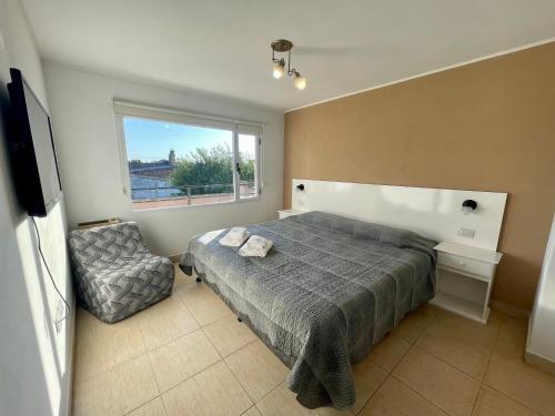 1 dormitorio con 1 cama, 1 silla y 1 ventana en Hermoso y cómodo dpto c/cochera Tres Arroyos en Tres Arroyos