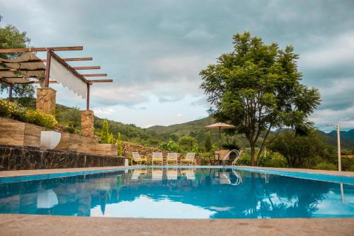 a swimming pool with chairs and a mountain in the background at Casa de Campo La Montaña in Tarija