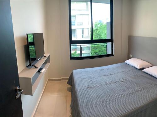 a bedroom with a bed and a flat screen tv at Hermoso depto. 1 dormitorio- Asuncion- Villa Morra #504 in Asunción