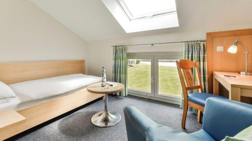 a bedroom with a bed and a table and a chair at Dorint Parkhotel Siegen in Siegen