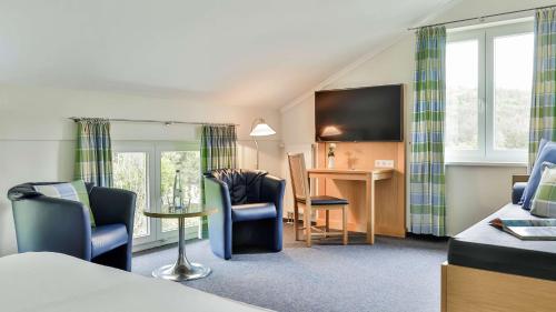 een hotelkamer met een bed en een tafel en stoelen bij Dorint Parkhotel Siegen in Siegen