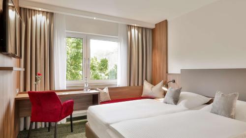 Pokój hotelowy z 2 łóżkami i biurkiem w obiekcie Dorint Parkhotel Siegen w mieście Siegen
