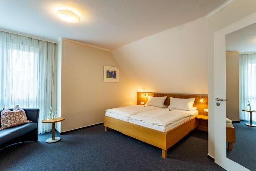 a hotel room with a bed and a couch at Dorint Parkhotel Siegen in Siegen