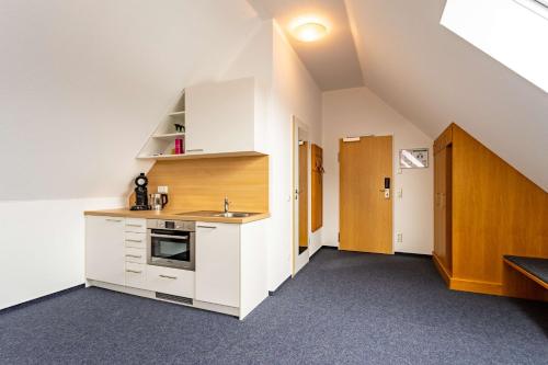 an attic kitchen with white cabinets and a sink at Dorint Parkhotel Siegen in Siegen