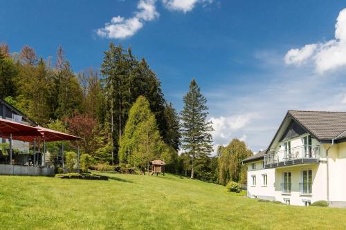 a white house on a green field with trees at Dorint Parkhotel Siegen in Siegen