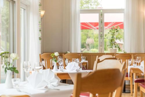 a restaurant with white tables and chairs and a window at Dorint Parkhotel Siegen in Siegen