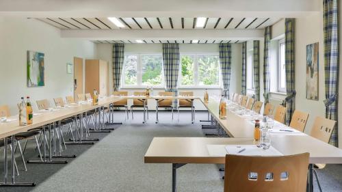 a large room with tables and chairs and windows at Dorint Parkhotel Siegen in Siegen