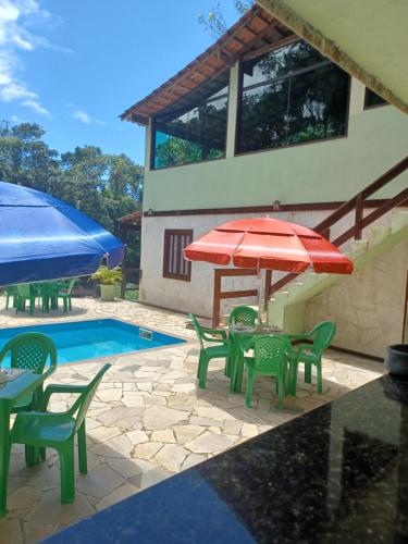 a patio with tables and chairs and a red umbrella at Avohai Lodge in Paraty