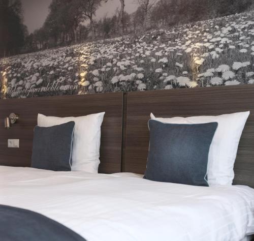 a bed with white sheets and blue pillows at Hotel De Bonte Wever Assen in Assen