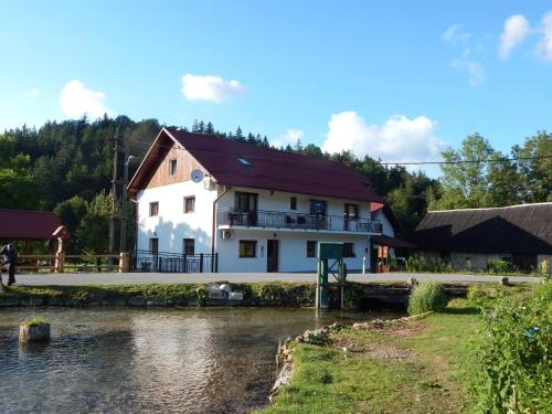un bâtiment à côté d'une rivière avec une maison dans l'établissement Guest House Končar, aux lacs de Plitvice