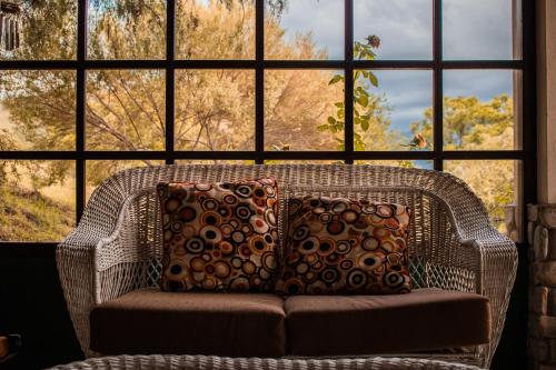 a wicker chair with pillows in front of a large window at Casa de Campo La Montaña in Tarija