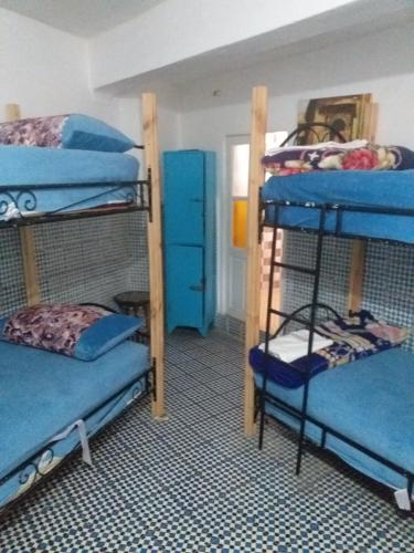 a room with three bunk beds with blue sheets at White And Blue in Essaouira