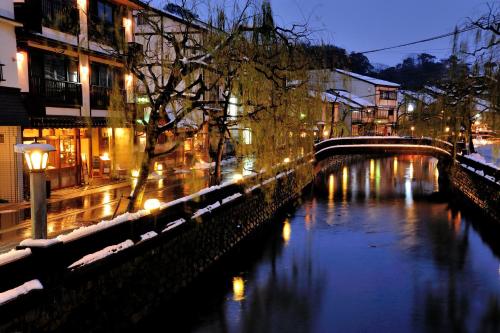 a river with buildings and a bridge at night at Kinosaki Yamamotoya in Toyooka