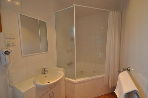 a white bathroom with a shower and a sink at Beachside Holiday Park in Normanville