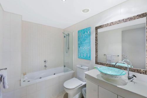 a bathroom with a sink and a tub and a toilet at Sandy Cove Apartment The Entrance 17 in The Entrance