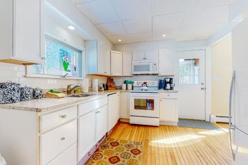 a kitchen with white cabinets and a wooden floor at A Villager's Dream in North Conway