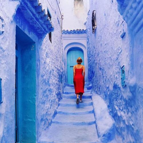 a woman walking down a alley in a blue building at Casa Plasa Grande CHEFCHAOUEN in Chefchaouene