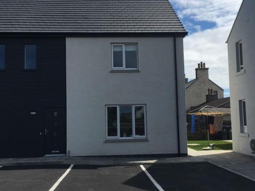 a white house with a window in a parking lot at Central Spacious 2 Bed 2 Bath, Free WiFi & Parking, Park View in Orkney