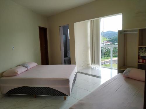 a bedroom with two beds and a large window at RECANTO BUSCAPE in Alto Caparao