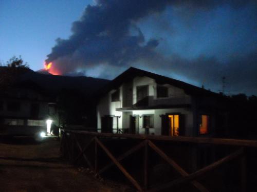 a house with a fire in the background at night at Aurora dell'Etna in Zafferana Etnea